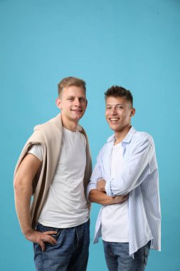 Portrait of happy brothers on light blue background