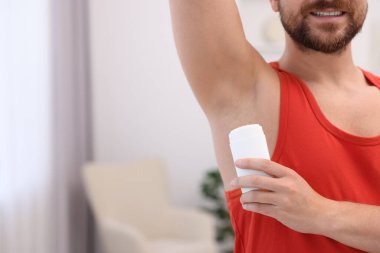 Gülümseyen adam evde deodorant sürüyor, yakın plan. Metin için boşluk
