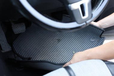 Gri lastik araba paspasını otomatikten alan adam, yakın plan.