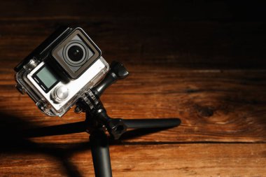 Ahşap yüzeyde modern aksiyon kamerası ve tripod. Metin için boşluk