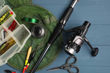 Dönen makaralı olta, yem, şamandıra, makas, mavi ahşap masa üzerinde ağ ve çizgi, üst görünüm