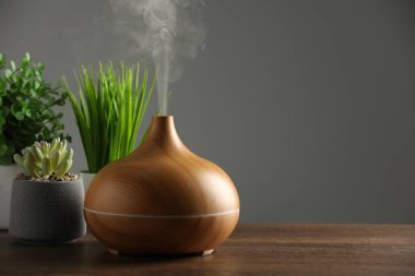 Aroma yağı yayıcı ve ahşap masa üzerinde ev bitkileri, metin için yer