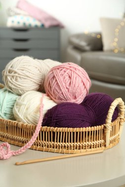 Renkli ipliklerle dolu hasır sepet, tığ işi desenler ve kapalı masa kancası.