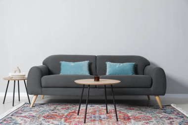 Rahat bir kanepe ve gri duvarın yanındaki masalar.