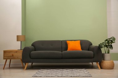 Yastıklı, sehpalı ve yeşil duvarlı şık bir kanepe.