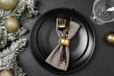 Tabaklar, çatal bıçak takımı, cam ve şenlik dekoru olan bir Noel sofrası.