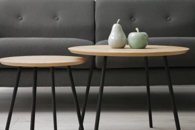 Rahat bir kanepe ve gri duvarın yanındaki masalar.