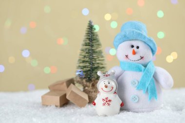 Tatlı kardan adamlar ve bej arka planda küçük Noel ağacı bulanık ışıklar, bokeh etkisi