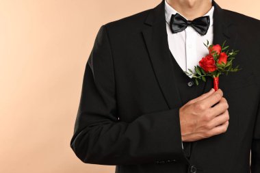 Takım elbiseli damat bej arka planda şık yaka çiçekleri, yakın plan. Metin için boşluk
