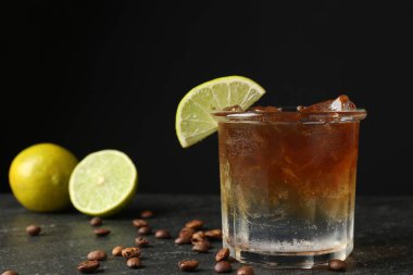 Koyu masada limon dilimi ve kahve çekirdekleri ile espresso tonik tazeleniyor.