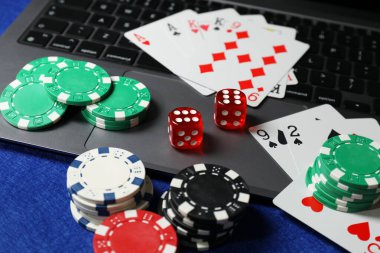 Poker fişleri, dizüstü bilgisayar, mavi masada kağıt ve zarlar. Çevrimiçi oyun