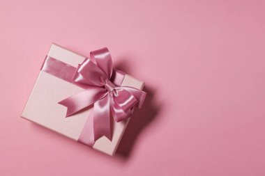 Tozlu pembe arka planda fiyonklu hediye kutusu, üst manzara