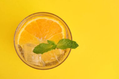 Portakallı taze su ve sarı arka planda nane şekeri, üst manzara. Metin için boşluk