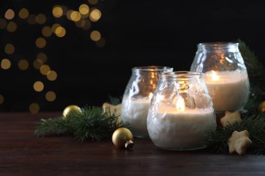 Yakıcı mumlar, takılar ve ahşap masada köknar ağacı dalları, yakın plan. Metin için boşluk