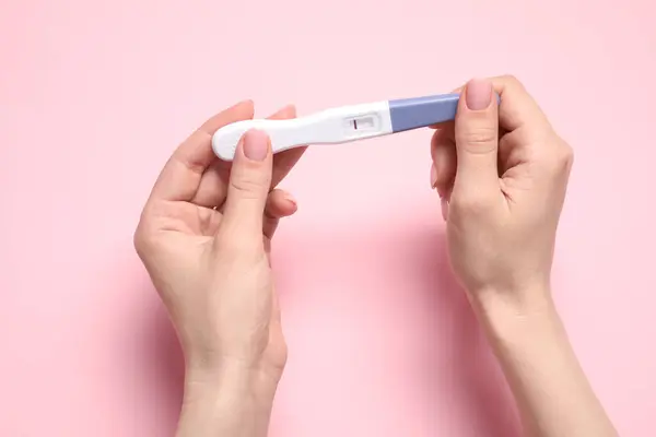 stock image Woman holding pregnancy test on pink background, closeup