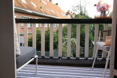 Güzel şakayıkları olan bir vazo ve rahat balkonda bir sandalye.