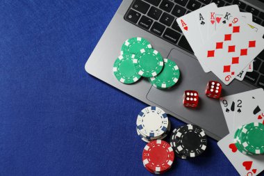 Çevrimiçi oyun. Poker fişleri, dizüstü bilgisayar, kağıt ve zarlar mavi masada, düz konum. Metin için boşluk