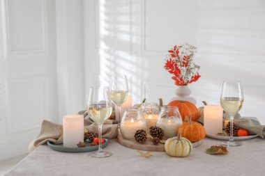 Sonbahar ayarı yanan mumlar, şarap bardakları ve dekorlar kapalı bir masada.