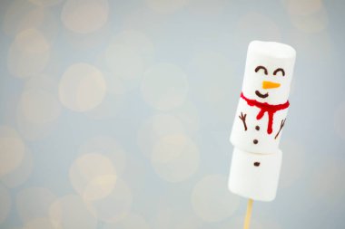 Işık arka planında bulanık ışıklarla marşmelovdan yapılmış komik kardan adam. Metin için boşluk