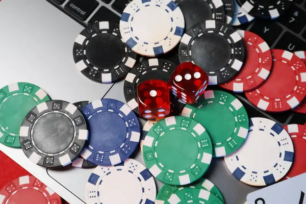 Poker fişleri, dizüstü bilgisayarlar ve zarlar kırmızı masanın üstünde. Çevrimiçi oyun