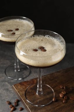 Bir bardak nefis espresso martini ve koyu dokulu masada kahve çekirdekleri.