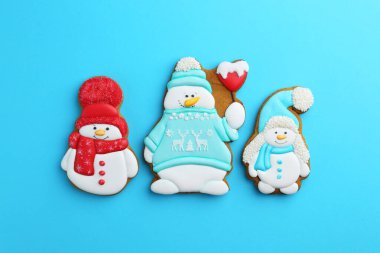 Açık mavi arka planda kardan adam şeklinde lezzetli Noel kurabiyeleri.