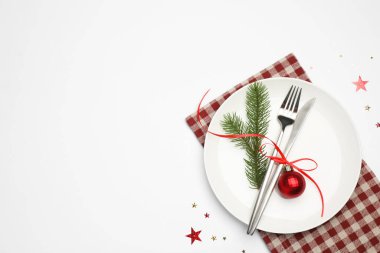 Beyaz arka planda tabak, çatal bıçak, peçete ve şenlik dekoruyla Noel sofrası. Metin için boşluk