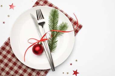 Beyaz arka planda tabak, çatal bıçak, peçete ve şenlik dekoruyla Noel sofrası. Metin için boşluk