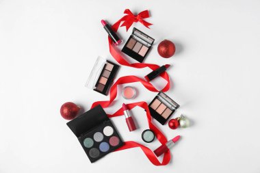 Beyaz arka planda makyaj ürünleri ve dekorla yapılmış Noel ağacı şekli
