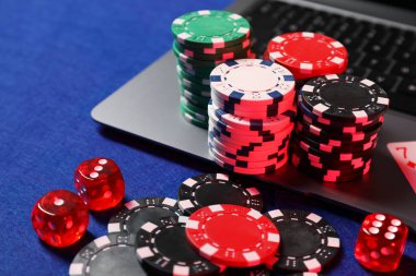 Poker fişleri, dizüstü bilgisayar ve zarlar mavi masada. Çevrimiçi oyun