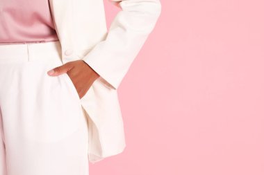 Pembe arka planda şık ceketli bir kadın, yakın plan. Metin için boşluk