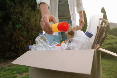 Geri dönüşüm konsepti. Dışarıdaki karton kutuya plastik şişe koyan adam.