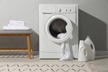Çamaşır makinesi, havlu ve deterjanlar çamaşır odasında.