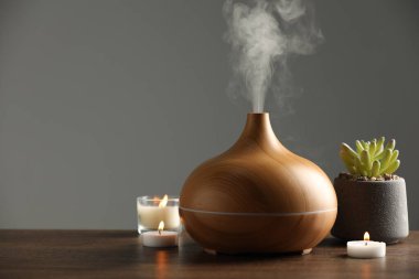 Aroma yağı yayıcı, ağaç masa üzerinde bitki ve yanan mumlar, metin için alan