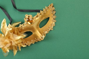 Yeşil arka planda bir altın karnaval maskesi, üst manzara. Metin için boşluk