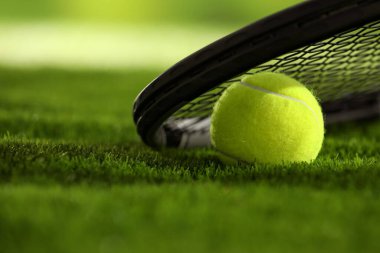 Tenis raketi ve top yeşil çimlerde, yakın plan. Metin için boşluk