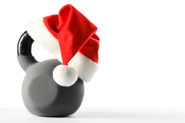 Kırmızı Noel Baba şapkalı kettlebell beyaza izole edilmiş.