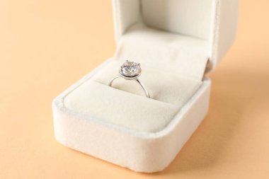 Bej arkaplanda değerli taşlı güzel bir yüzük, yakın plan.