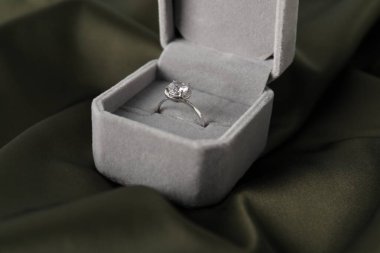 Koyu renk kumaş üzerinde değerli taşlı güzel bir yüzük, yakın plan.