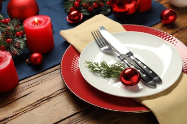 Tabaklar, çatal bıçak takımı ve ahşap masa üzerindeki şenlikli Noel yeri seti, yakın plan.