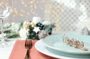 Tabakları, çatalı ve şenlikli dekorları olan bir Noel sofrası.