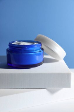 Açık mavi arkaplana karşı kavanozdaki yüz kreminin şık sunumu