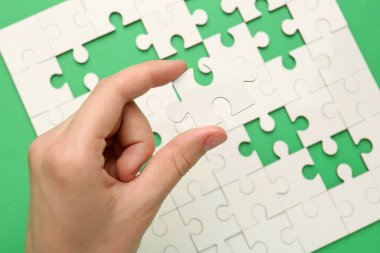 Yeşil arka planda beyaz bulmacayı çözen kadın, yakın plan