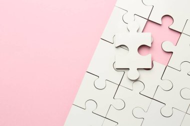 Pembe arka planda beyaz yapboz parçaları, üst manzara. Metin için boşluk