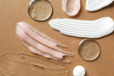 Kahverengi arka planda farklı kozmetik ürünlerinin kokusu, düz yatış