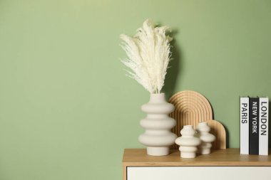 Güzel dekoratif bitkiler, vazolar, ahşap tahtalar ve içinde yeşil duvarın yanındaki çekmecelerin isimlerinin yazılı olduğu ciltli kitaplar.