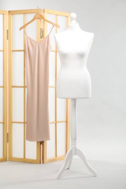 Bir kadın manken ve parlak arka planda elbisesi olan katlanmış bir ekran.