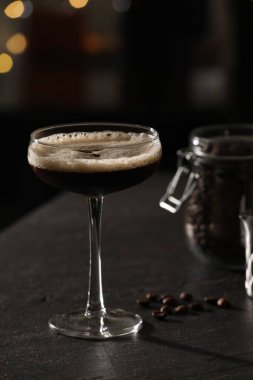 Lezzetli espresso martini ve kahve çekirdekleri ile koyu renkli masada bulanık ışıklara karşı.