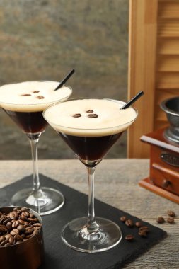 Bir bardak nefis espresso martini, kahve çekirdekleri ve ahşap masa.