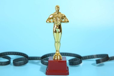 Altın Oscar ödülü ve açık mavi arka planda film makarası